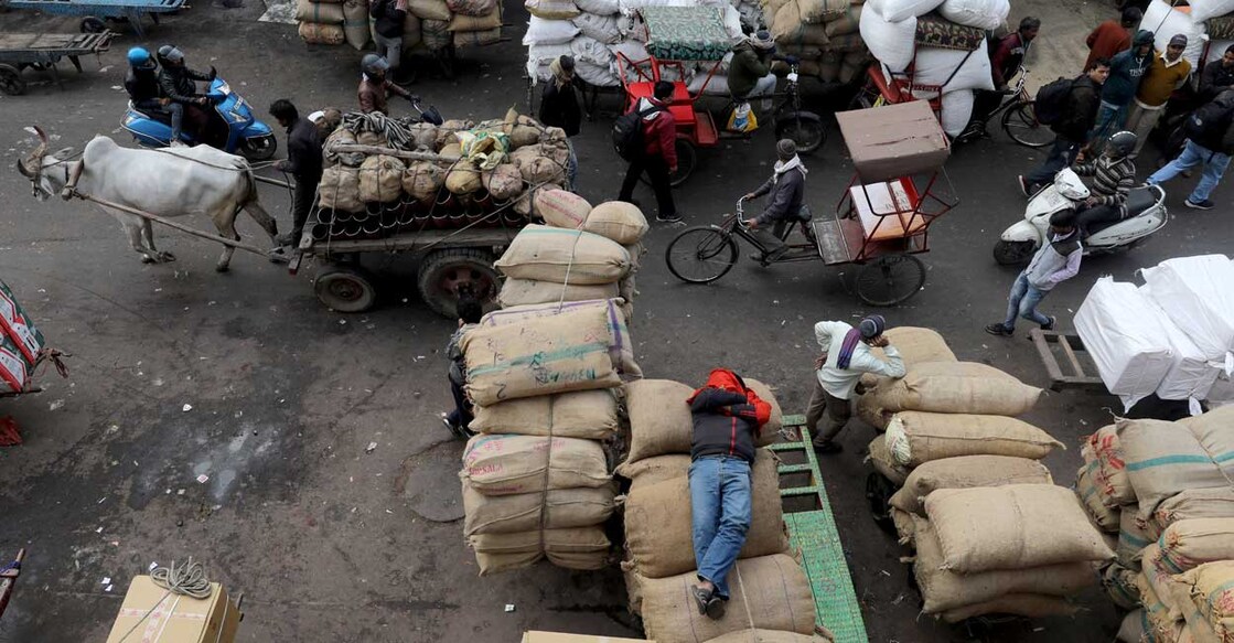 A labourer sleeps on sacks as traffic moves past him in a wholesale market in the old quarters of Delhi, January 7, 2020. Photo: REUTERS/Anushree Fadnavis