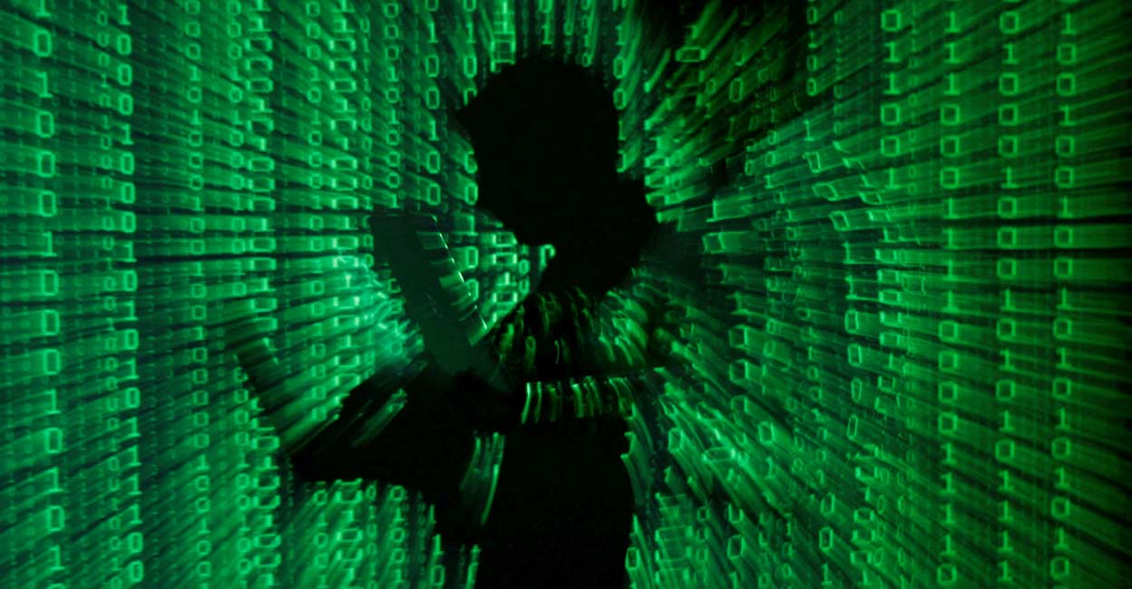 An illustration picture shows a projection of binary code on a man holding a laptop computer. File Photo: Reuters/Kacper Pempel