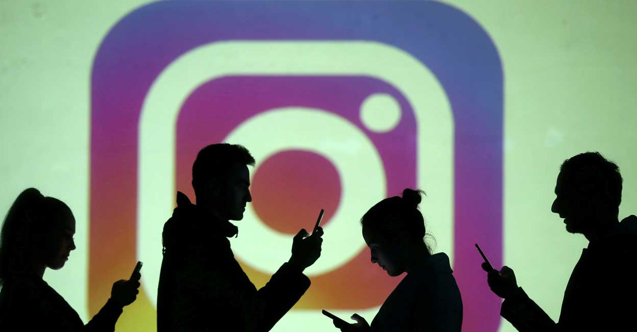 FACEBOOK-INSTAGRAM-CHILDREN Silhouettes of mobile users are seen next to a screen projection of Instagram logo in this picture illustration taken March 28, 2018. REUTERS/Dado Ruvic/Illustration/File Photo