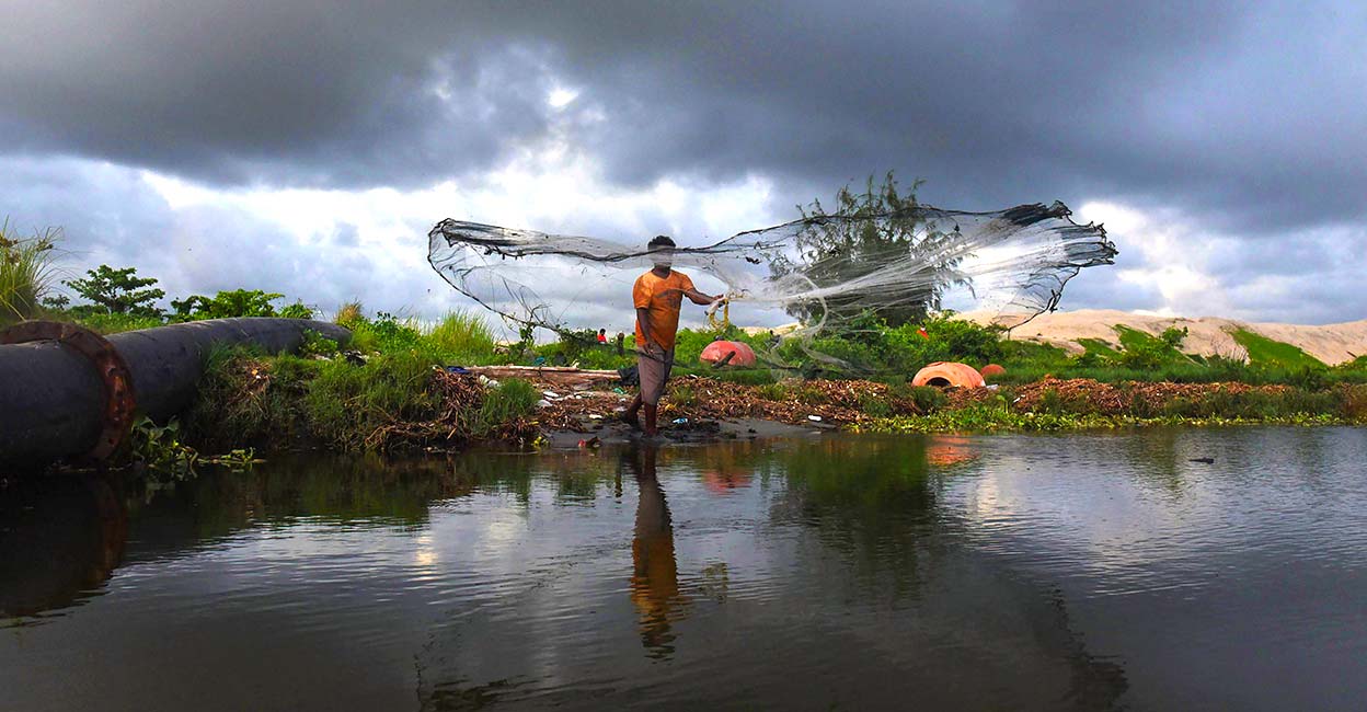 Monsoon A fisherman casts his net as dark clouds hover in the sky after the South West monsoon made its footfall in Kerala. PTI