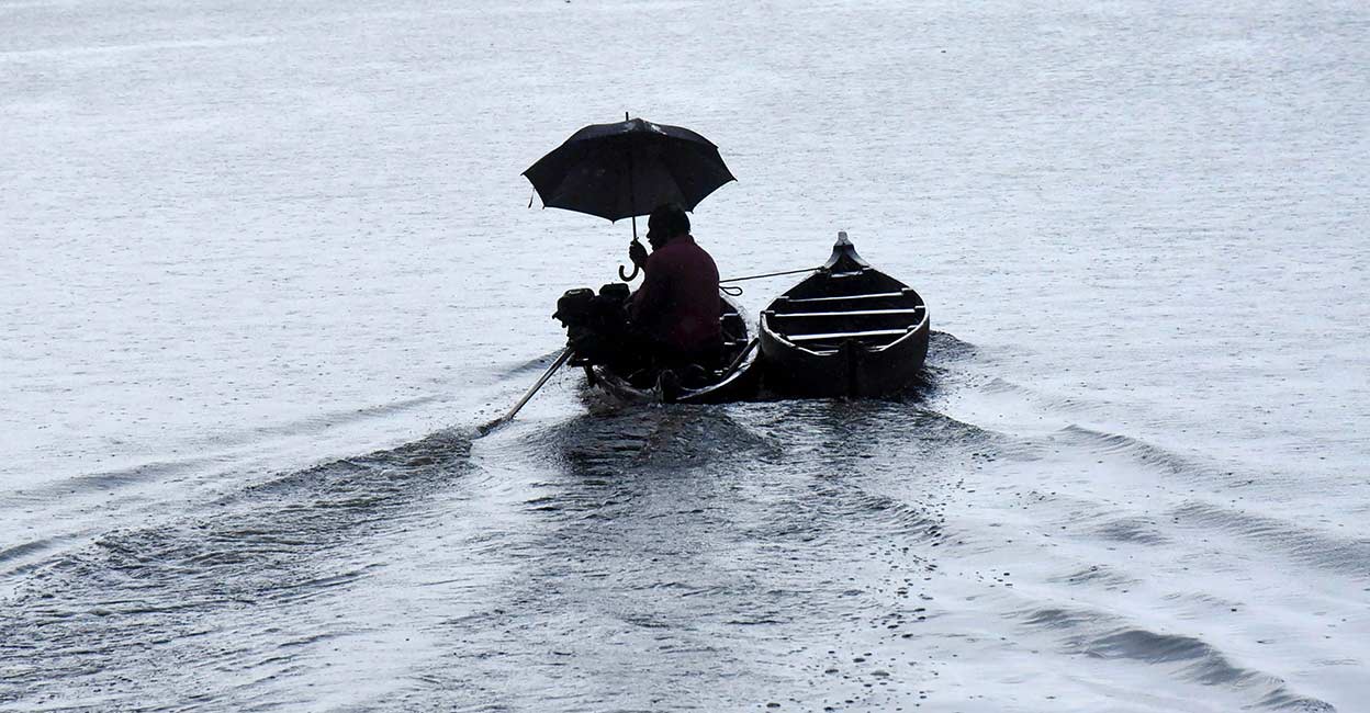 Monsoon A man holds an umbrella as he rows a boat during rain after South West monsoon made landfall in Kerala. PTI