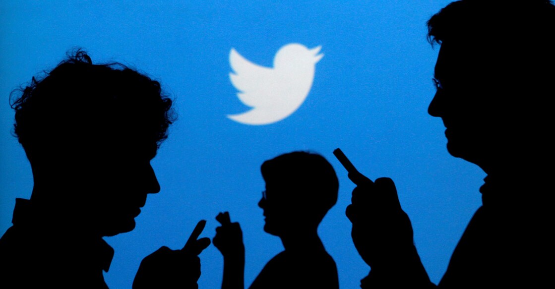 People holding mobile phones are silhouetted against a backdrop projected with the Twitter logo in this illustration picture taken September 27, 2013. REUTERS/Kacper Pempel/Illustration/File Photo
