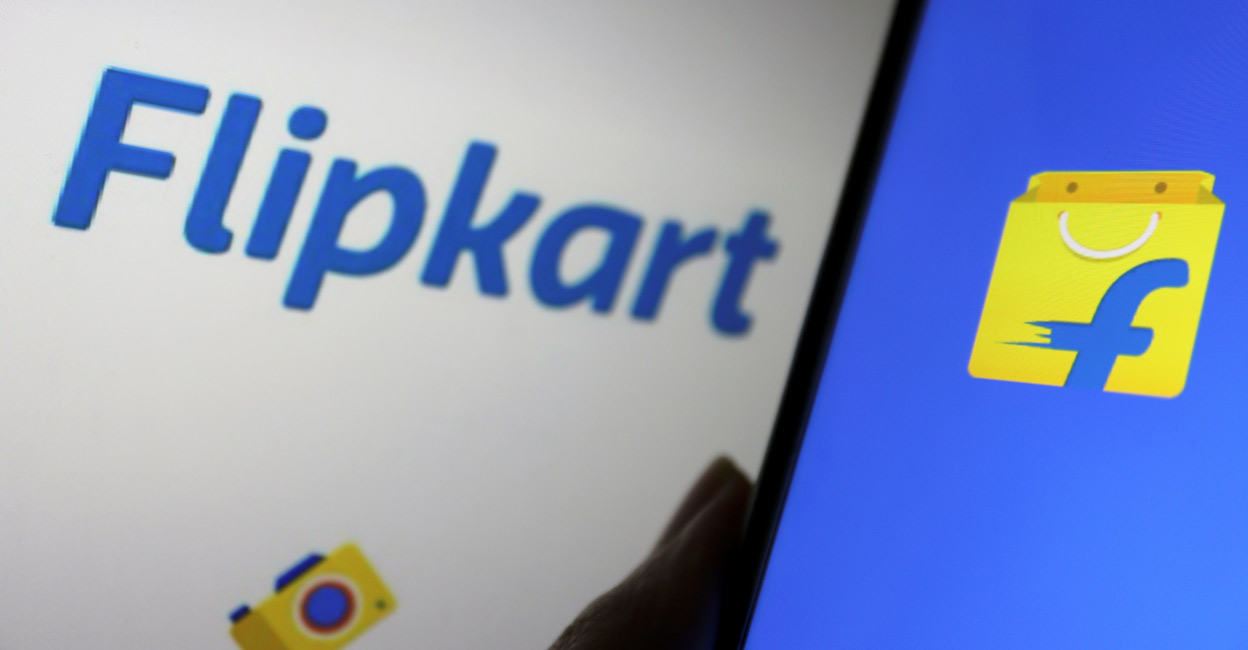 A mobile phone showing the logo of Indian online retailer Flipkart is seen in front of its sign. File Photo: REUTERS/Florence Lo/Illustration
