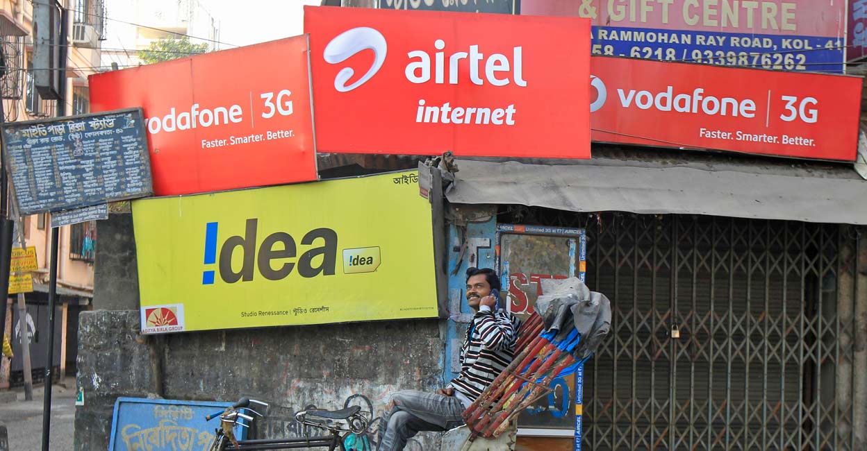 A rickshaw puller speaks on his mobile phone as he waits for customers in front of advertisement billboards belonging to telecom companies in Kolkata February 3, 2014. Reuters/Rupak De Chowdhuri/Files