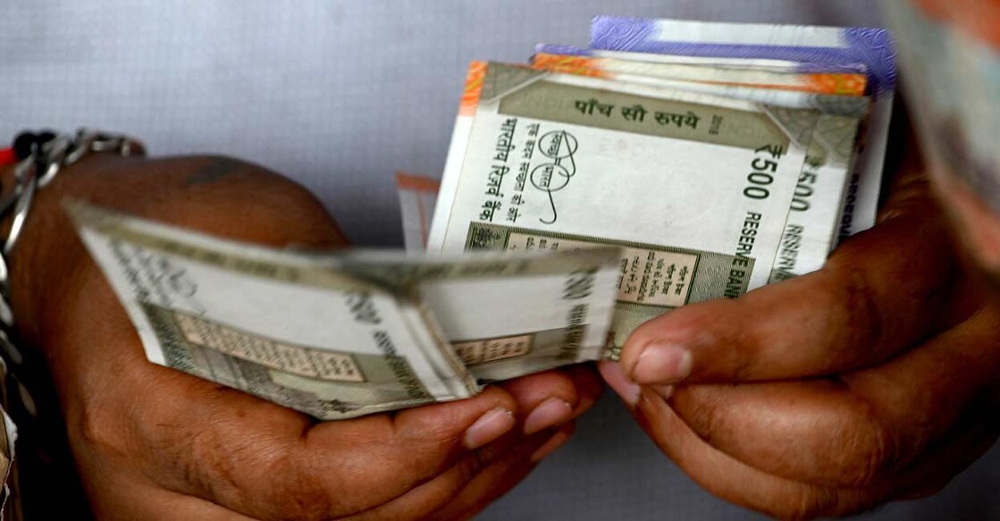 A fruit vendor counts Indian rupee notes in Mumbai on May 9, 2022. Photo: Indranil Mukherjee/AFP