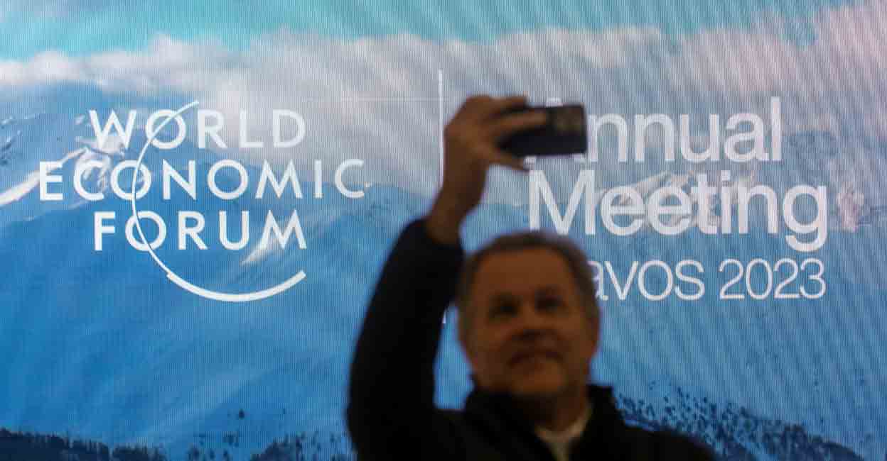 WEF A man takes a selfie in front of the logo of the World Economic Forum (WEF) 2023 at Davos Congress Centre in the Alpine resort of Davos, Switzerland, January 15, 2023. REUTERS/Arnd Wiegmann
