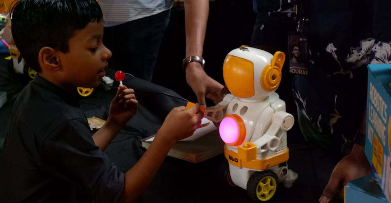 A child interacts with a small robot at the expo. Photo: Manorama