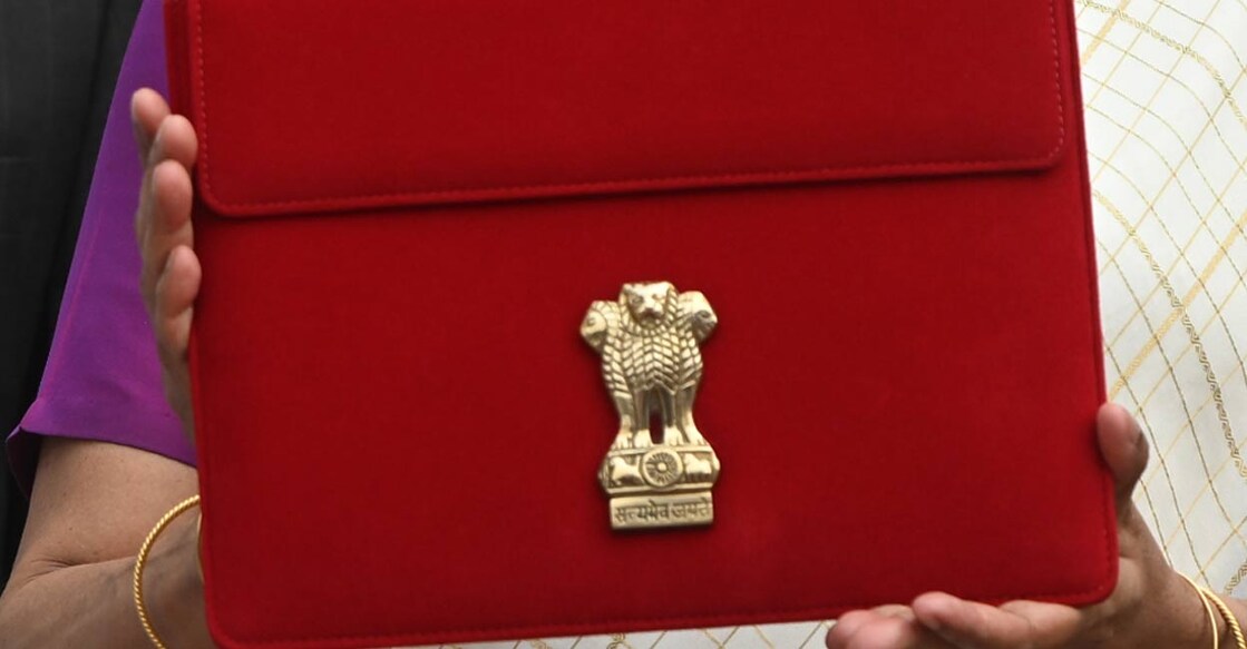 Union Finance Minister Nirmala Sitharaman displays a red pouch carrying the Budget documents outside the Finance Ministry in North Block before leaving for the Parliament where she will table the Union Budget 2024-25, in New Delhi, Tuesday, July 23, 2024. Photo: PTI. 