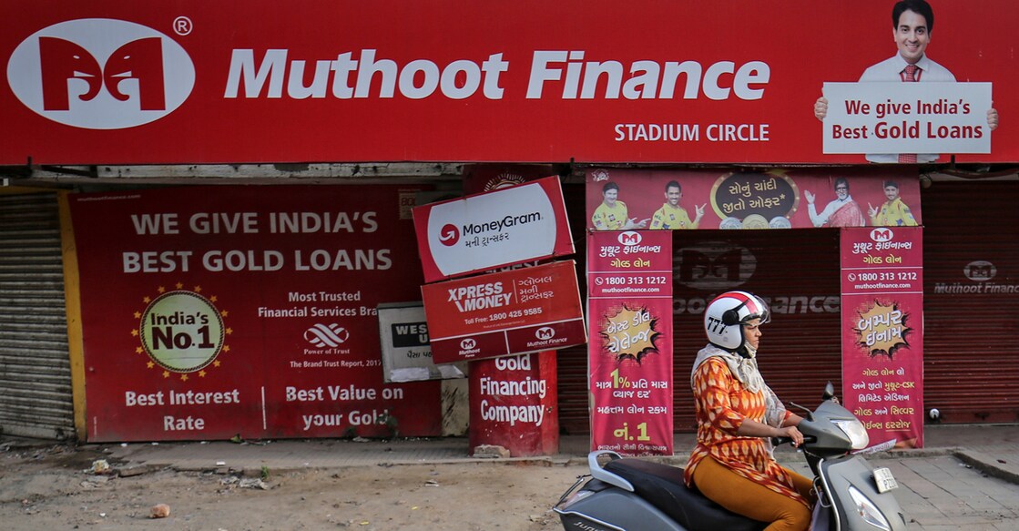 A woman rides her scooter past a Muthoot Finance branch in Ahmedabad, India, August 21, 2019. REUTERS/Amit Dave/File photo