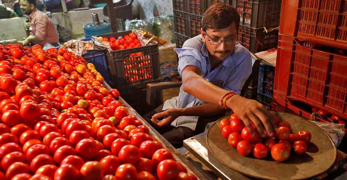 FILE PHOTO: A vendor weights tomatoes for a customer at a vegetable market in Ahmedabad, India, July 25, 2023. REUTERS/Amit Dave/File Photo