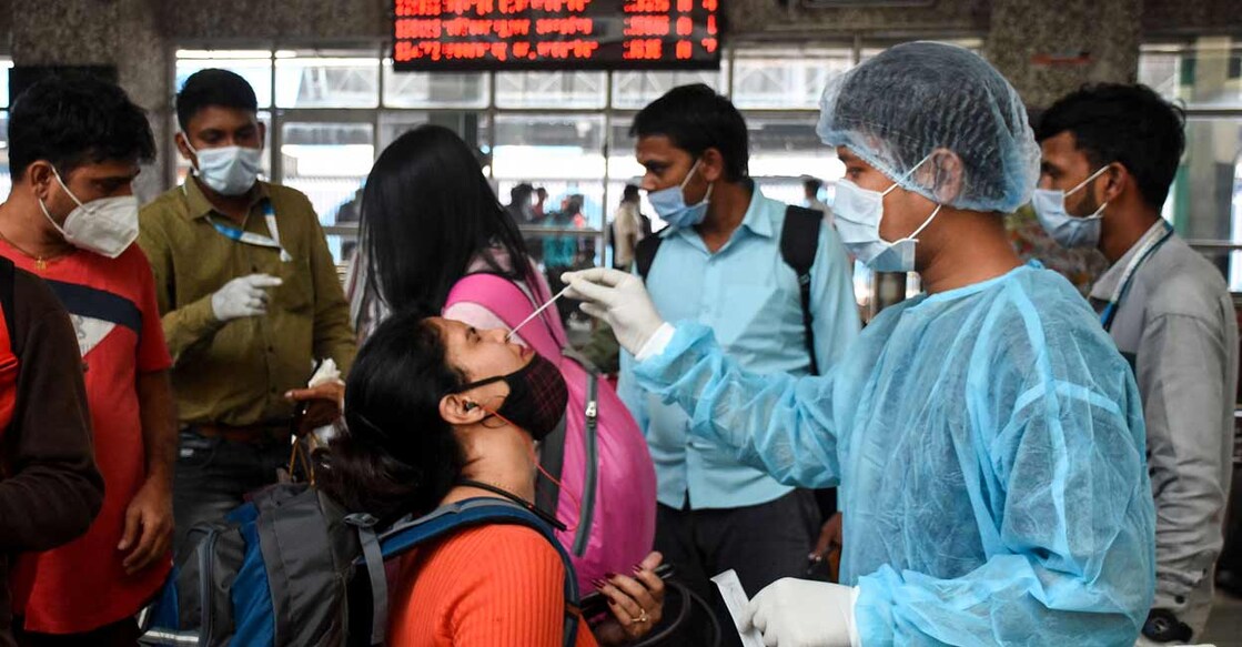 A healthcare worker collects a swab sample of a passenger for COVID-19 test, at Bandra Terminal, in Mumbai, Thursday, Dec. 9, 2021. Photo: PTI