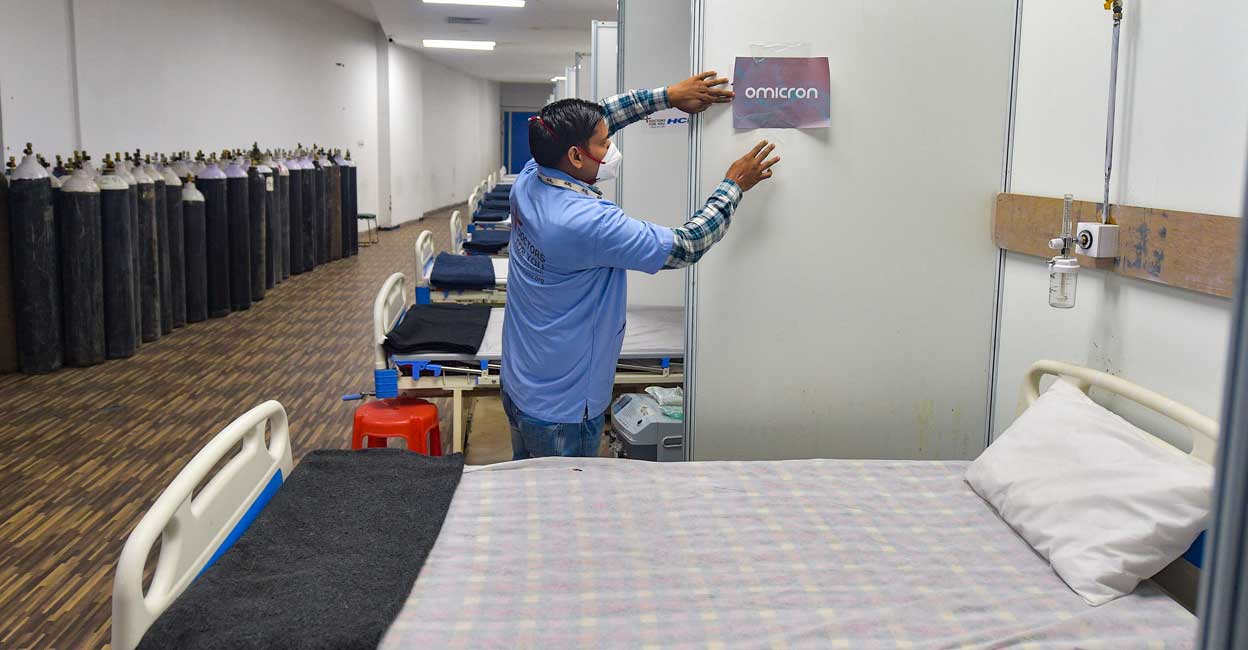 A worker pastes a sticker on a wall of a COVID-19 facility at Commonwealth Games Village in view of the rising Omicron cases in New Delhi, Wednesday, Dec. 22, 2021. Photo: PTI