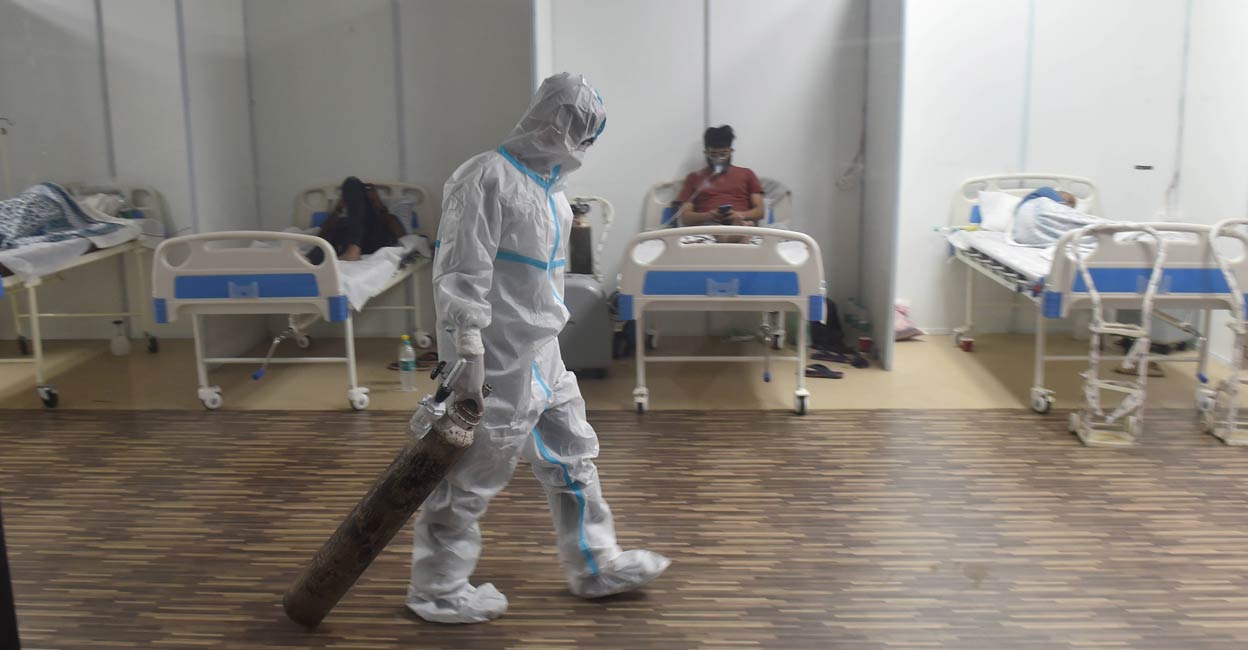 A doctor drags an oxygen cylinder at CWG village Covid-19 Care Centre near Akshardham, in New Delhi, Tuesday, April 20, 2021.  Photo: PTI