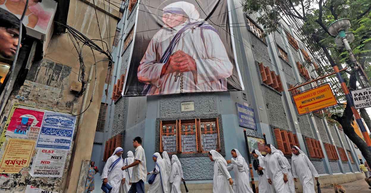 Nuns belonging to the global Missionaries of Charity, walk past a large banner of Mother Teresa ahead of her canonisation ceremony, in Kolkata, India September 3, 2016. Reuters/Rupak De Chowdhuri