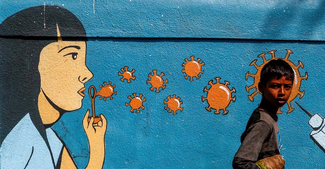 A boy walks past a graffiti amidst the spread of the coronavirus disease (COVID-19) on a street in Navi Mumbai, India, March 5, 2021. REUTERS/Francis Mascarenhas