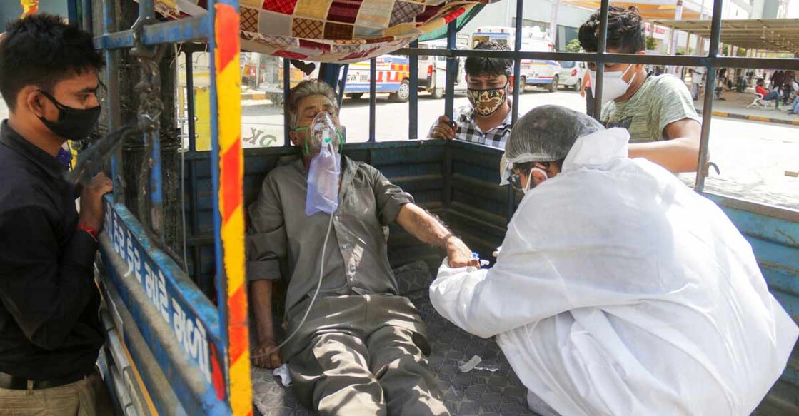 COVID-19 positive patient get primary treatment inside a tempo as he waits to be admitted in a COVID-19 hospital in Ahmedabad, Wednesday, April 28, 2021. Photo: PTI