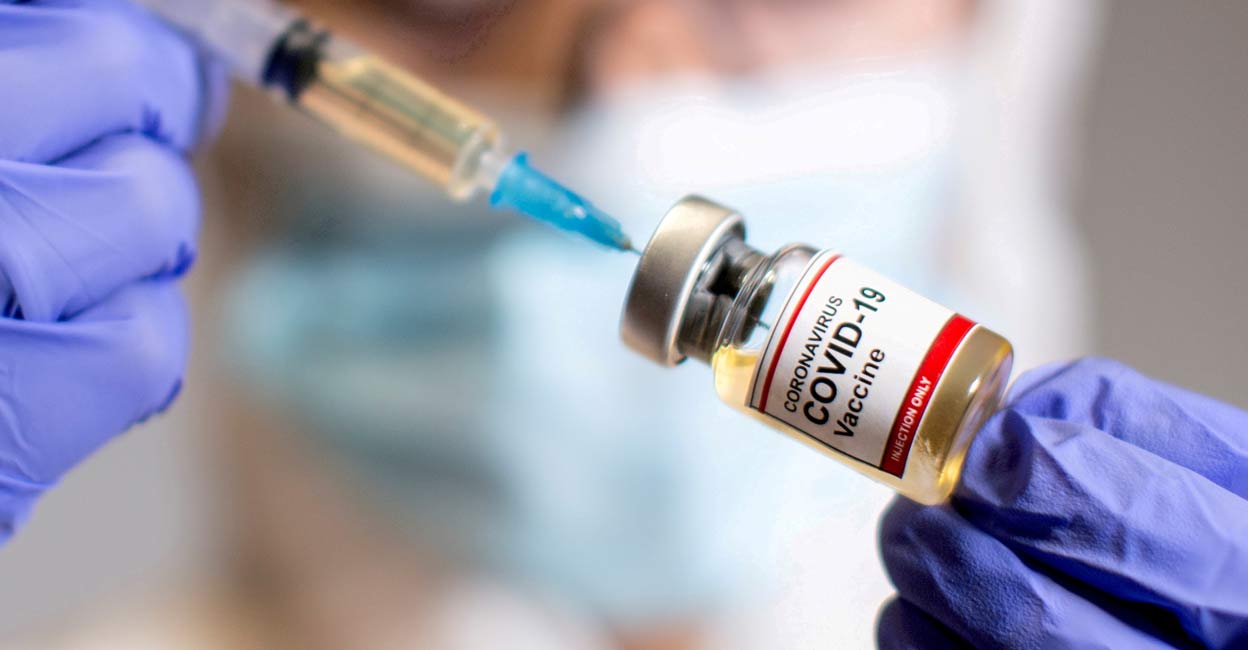 A woman holds a small bottle labelled with a "Coronavirus COVID-19 Vaccine" sticker and a medical syringe in this illustration taken  October 30, 2020. Reuters/Dado Ruvic
