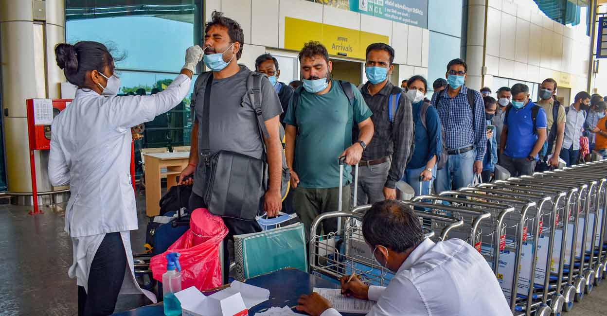 A health worker collects swab sample of a passenger for Covid-19 test, at a airport in Prayagraj, Friday, August 13, 2021. Photo: PTI