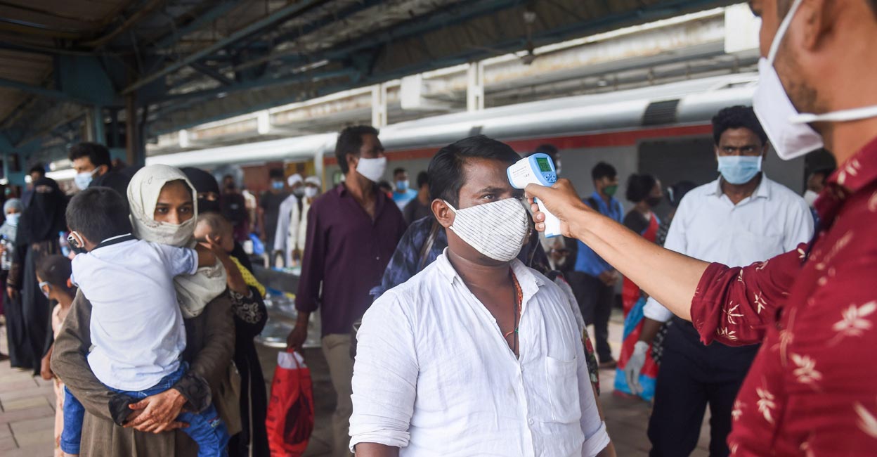 A BMC health worker does thermal screening of a passenger for COVID-19 test, at Dadar railway station in Mumbai, Thursday, Aug. 5, 2021. PTI