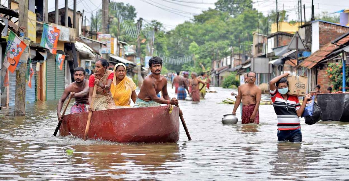 People wade through a flooded street to collect food and drinking water from a distribution centre in Amta town of Howrah district in the eastern state of West Bengal, India, August 5, 2021. REUTERS