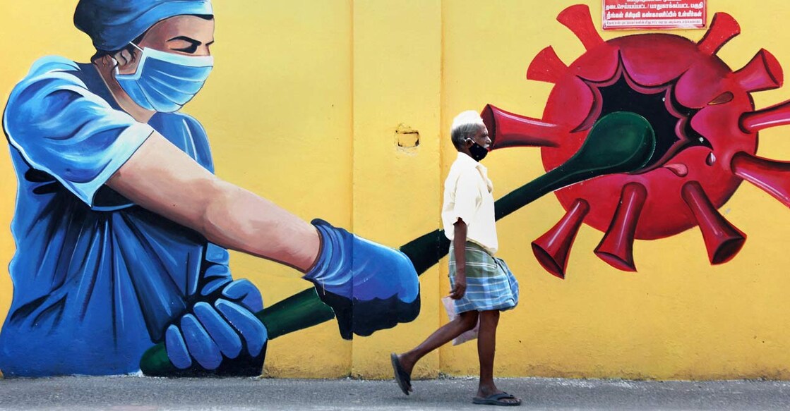 COVID-19 in India People walk past a wall mural on COVID awareness in Chennai, Saturday, Sept. 18, 2021.