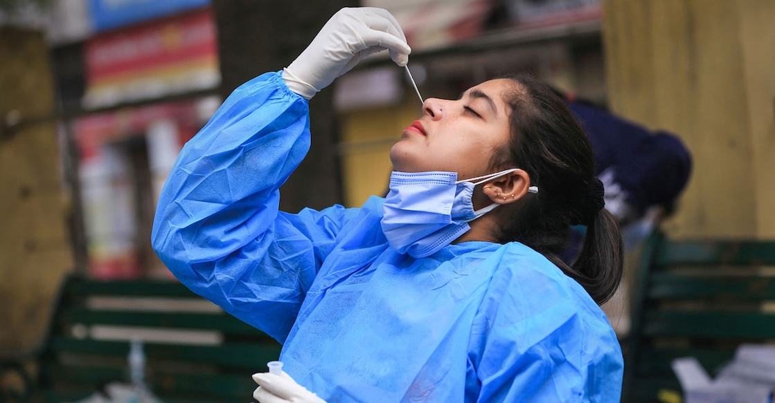 A healthworker conducts a COVID-19 test on herself, during weekend restrictions in Jammu, Sunday, Jan. 16, 2022. Photo: PTI