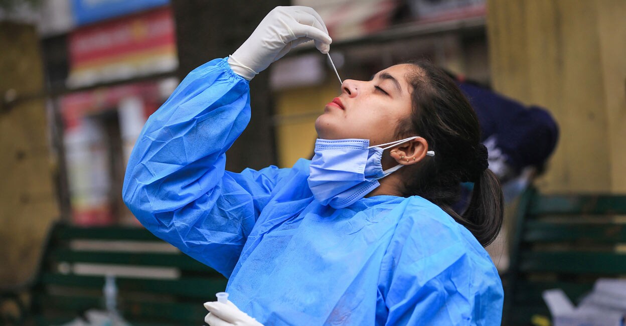 A healthworker conducts a COVID-19 test on herself, during weekend restrictions in Jammu, Sunday, Jan. 16, 2022. Photo: PTI