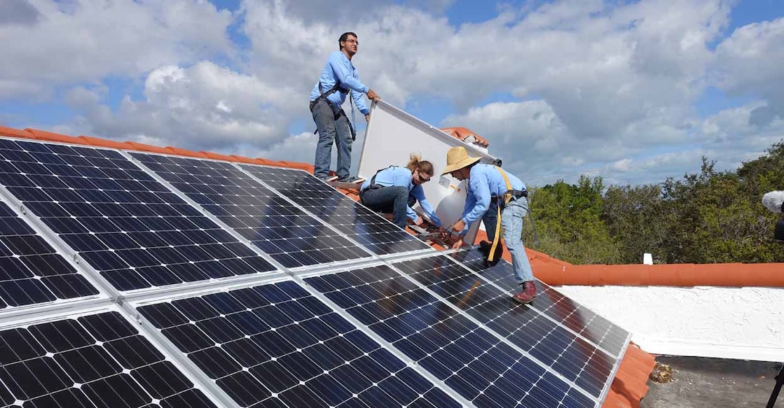 Workers install solar panels on a rooftop at a home in Palmetto Bay, Florida. Photo by Kerry Sheridan/AFP
