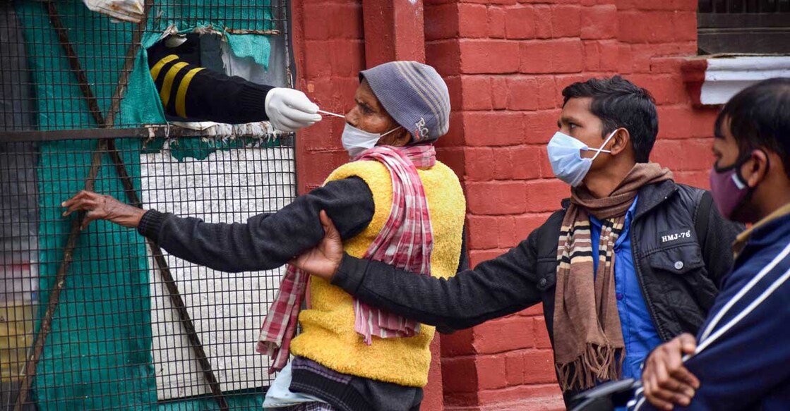 A health worker collects a swab sample of a man for COVID-19 test, amid concern over rising Omicron cases, in Prayagraj, Monday, January 24, 2021. Photo: PTI