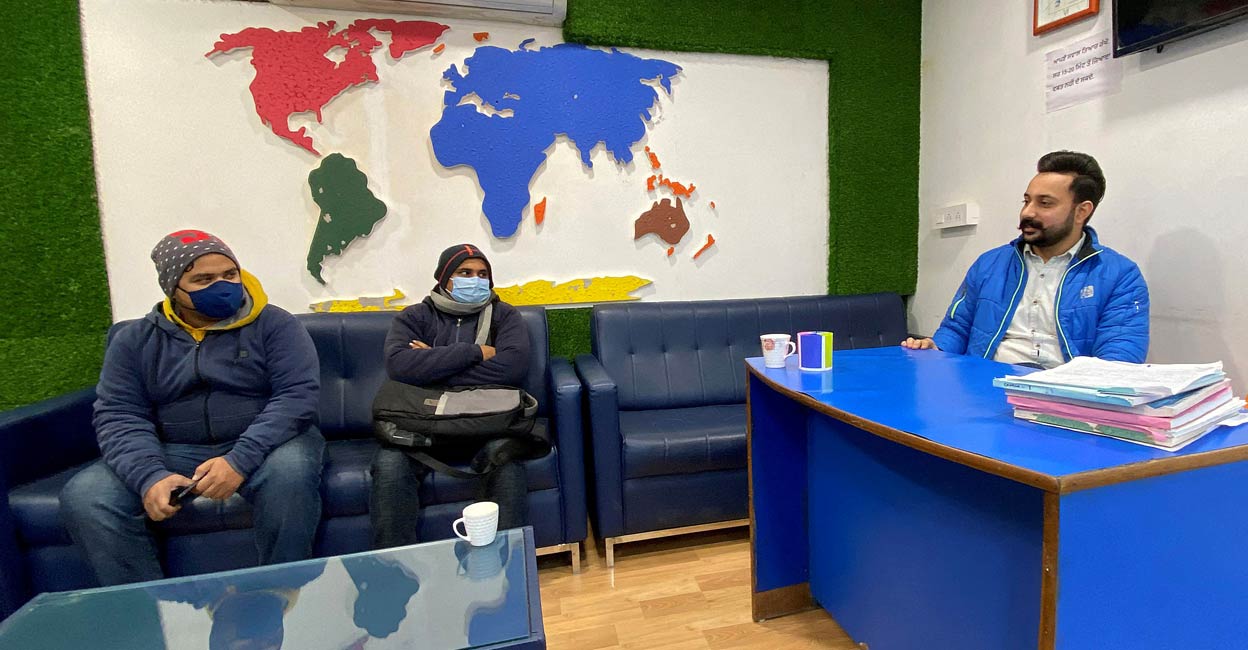 Srijan Upadhyay and Sagar Sharma from the eastern state of Bihar listen to Lovepreet, an immigration counsellor of Blue Line consultants, at his office in Rajpura town in Punjab. Photo: Reuters/Krishna N. Das