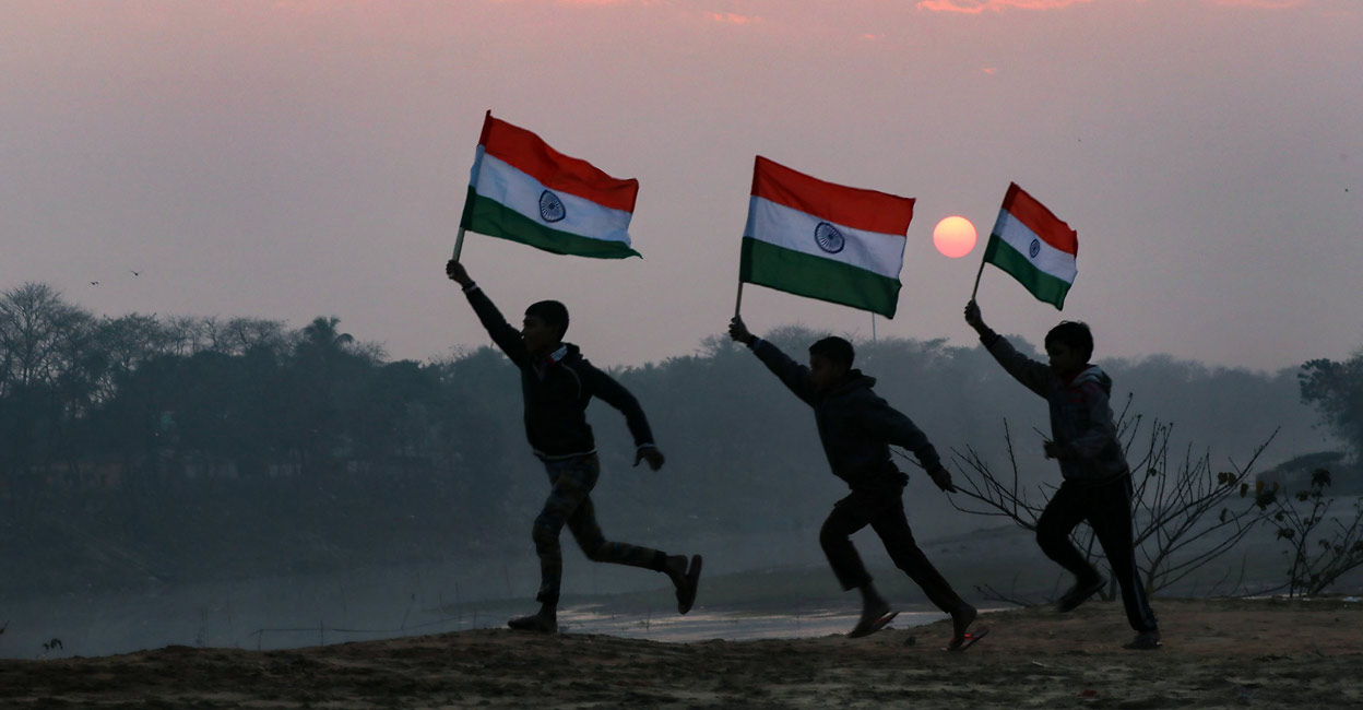 Children hold the Tricolor during sunset, on the eve of Republic Day 2022. Photo: PTI