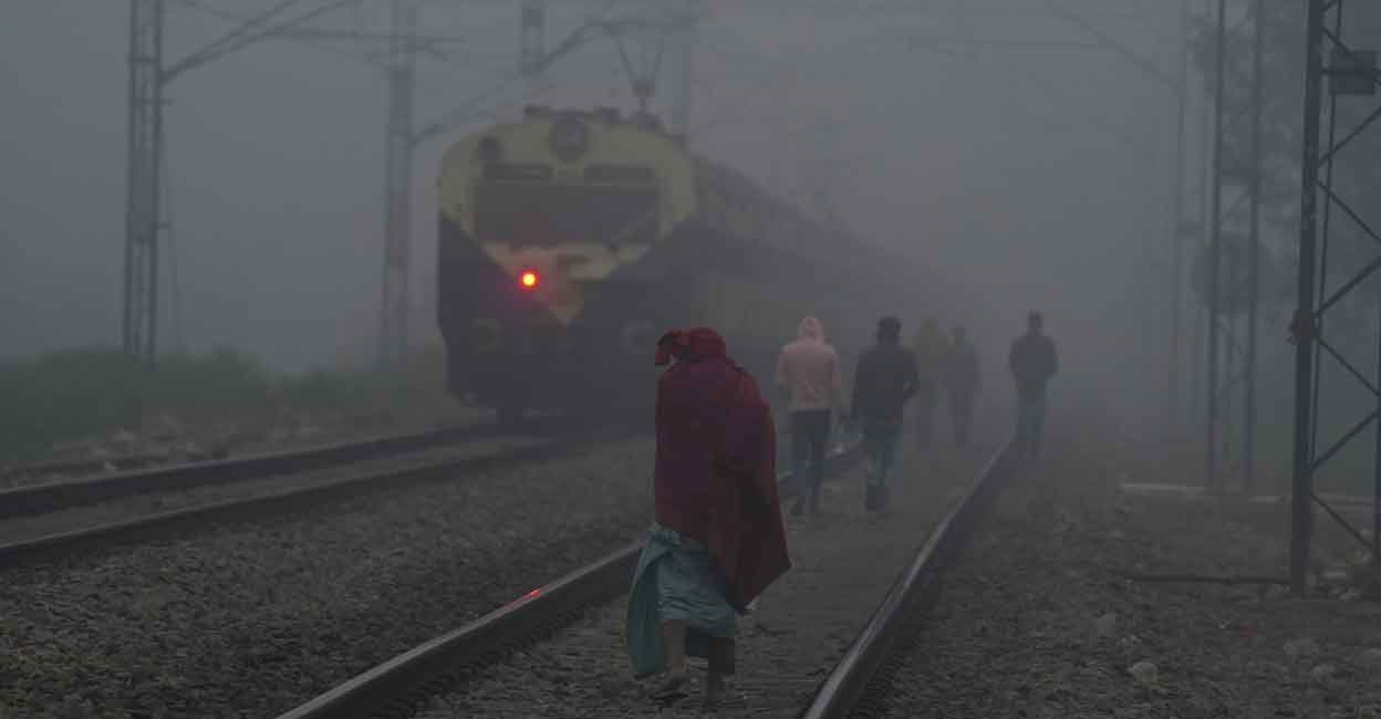 People walk on a railway track during a cold and foggy morning, in New Delhi, Monday, Dec. 26, 2022. Photo: PTI