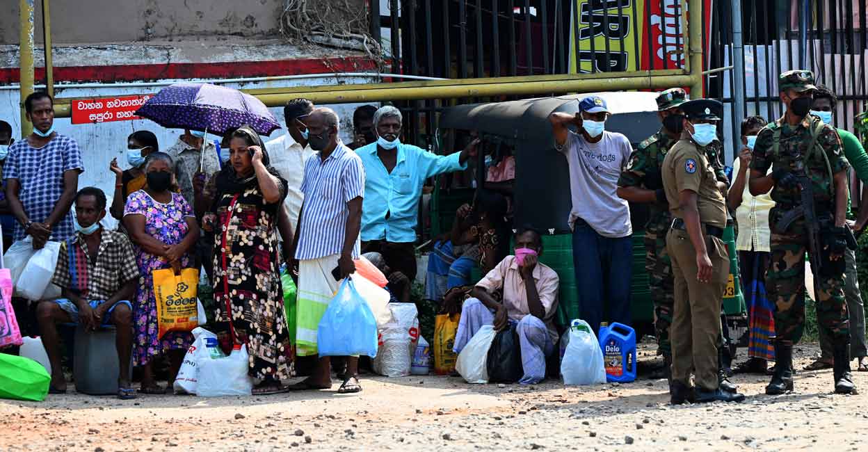 Soldiers guard a service station as people wait to get fuel in Colombo on March 23, 2022.  The South Asian island nation is grappling with its worst economic meltdown in over seven decades, with rolling electricity blackouts and essential goods such as food and cooking gas also in short supply. Photo: by Ishara S. Kodikara/AFP