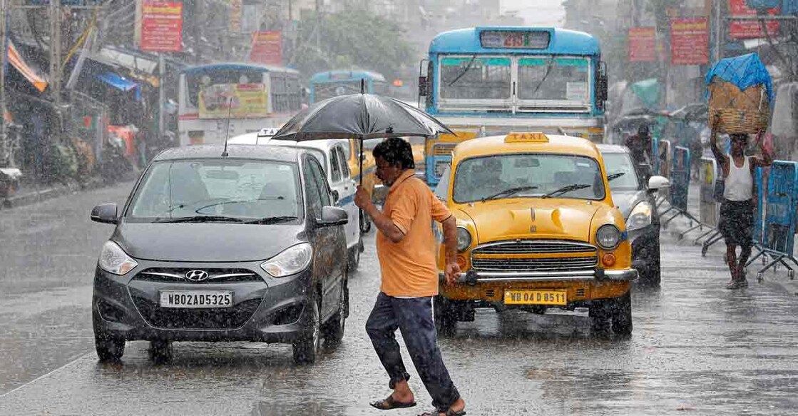A man carrying an umbrella runs as he crosses a busy road during rain in Kolkata, India, July 10, 2018. FILE PHOTO: REUTERS/Rupak De Chowdhuri