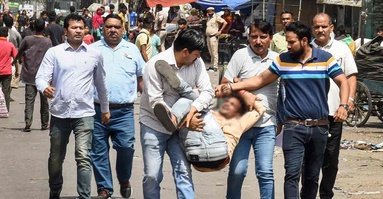 PTI04_18_2022_000065A Delhi Police personnel detain a person, after clashes broke out between two communities during a Hanuman Jayanti procession on Saturday, at Jahangirpuri in New Delhi, Monday, April 18, 2022. (PTI Photo/Shahbaz Khan)