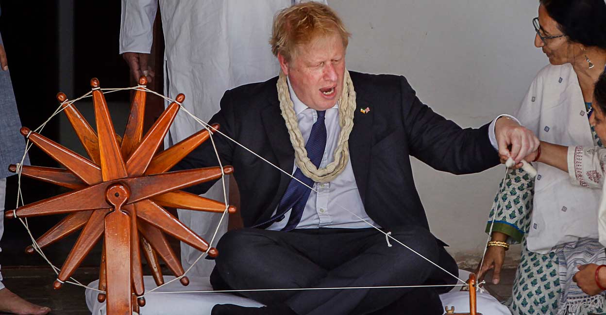 PTI04_21_2022_000037A Boris Johnson tries his hands on a spinning wheel during a visit to the Sabarmati Gandhi Ashram. Photo: PTI