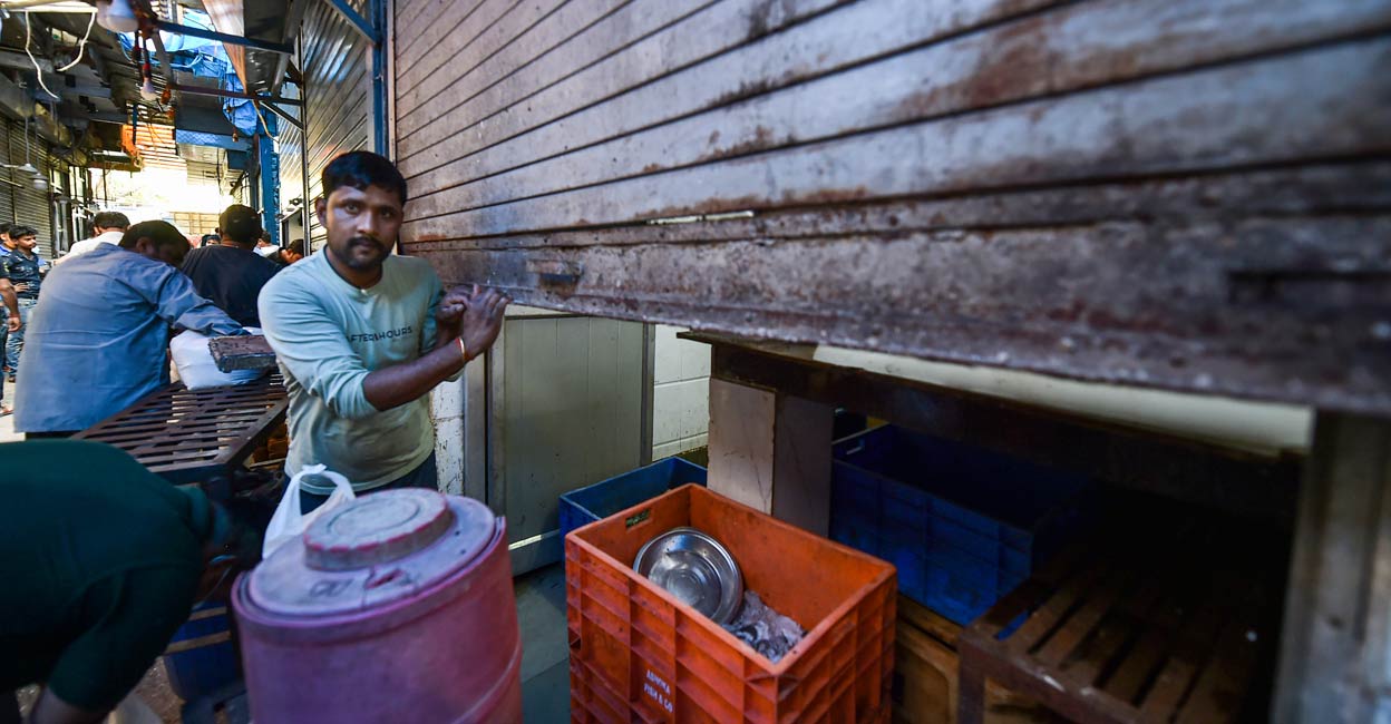A worker closes the shutter of a meat shop at INA market in New Delhi, Tuesday, April 5, 2022. Photo: PTI/Arun Sharma