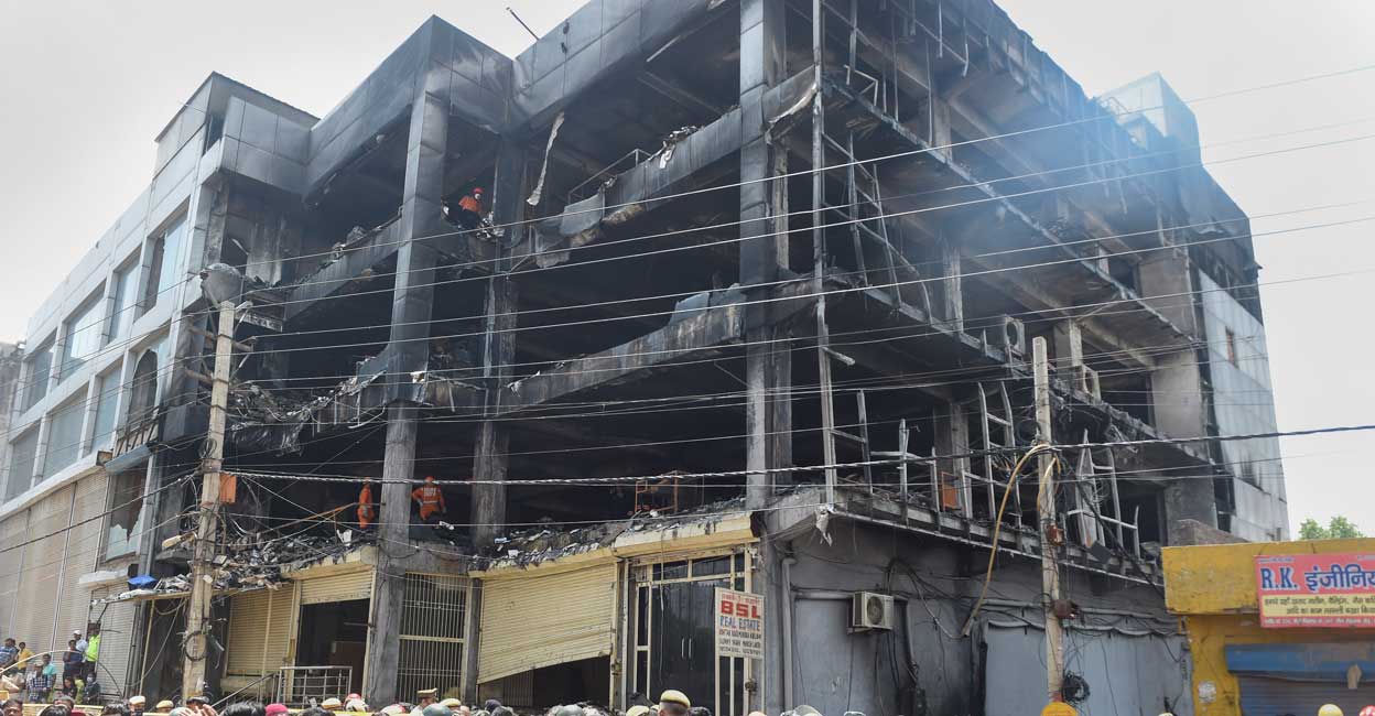 Journalists, security personnel and civil defence officials at the site, as NDRF personnel carry out rescue and relief work after a massive fire at an office building near the Mundka Metro Station, in West Delhi. Photo: PTI/Atul Yadav