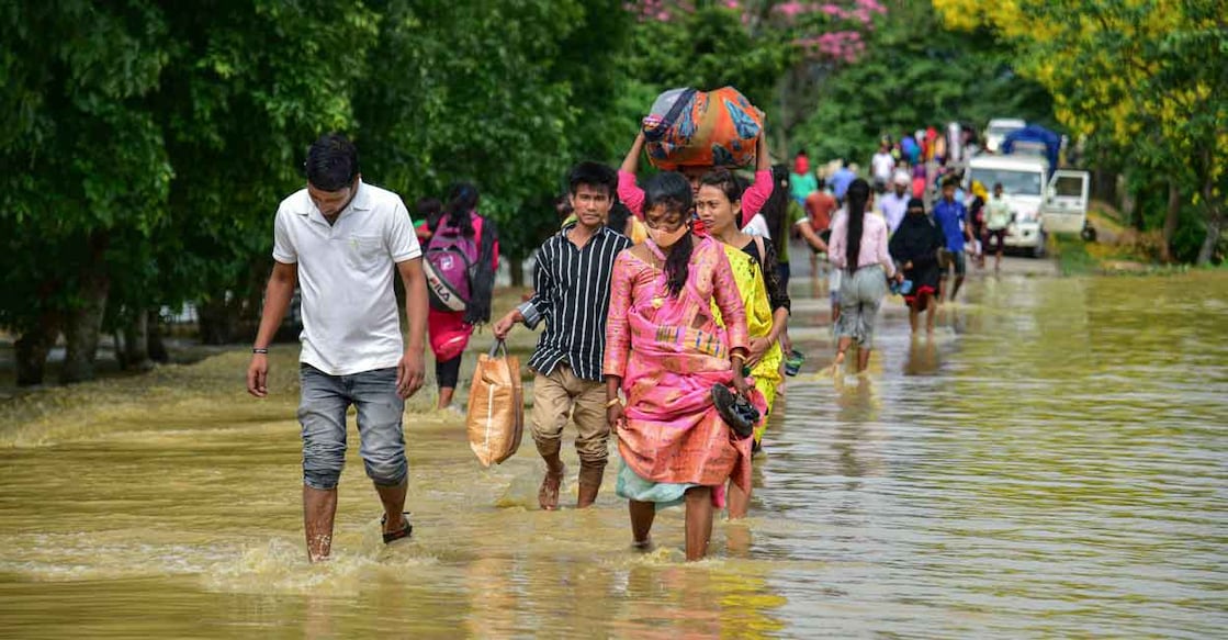 Villagers wade through a flooded road after rain at a village in Nagaon District, Tuesday, May 17, 2022. Photo: PTI