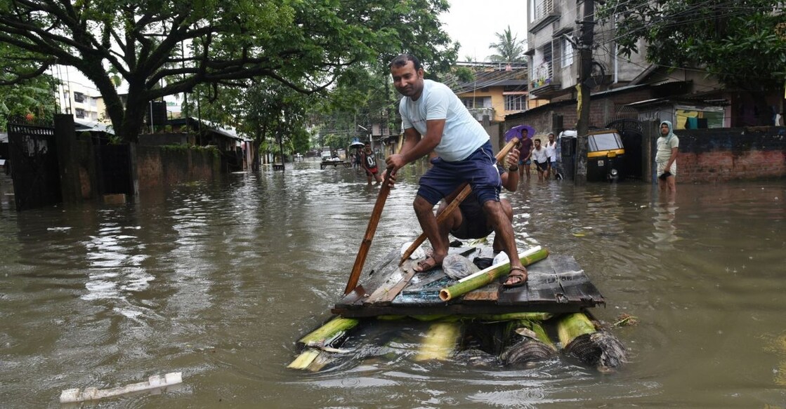 Guwahati rain A man on a temporary bamboo boat crosses a flooded road after heavy rain in Guwahati, Tuesday, June 14, 2022. Photo: Anuwar Hazarika/IANS