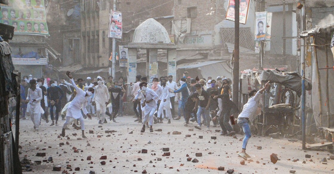 People throw stones during clashes in Kanpur on Friday. Photo: PTI