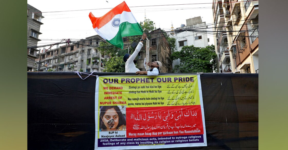 People hold up the national flag of India before the start of a protest demanding the arrest of BJP member Nupur Sharma. Photo: Reuters