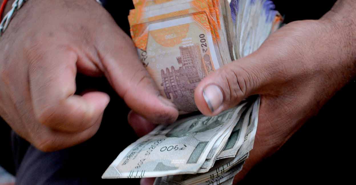 A fruit vendor counts a wad of Indian Rupee currency notes for payment at his roadside stall in Mumbai on July 19, 2022.  File Photo:  INDRANIL MUKHERJEE / AFP