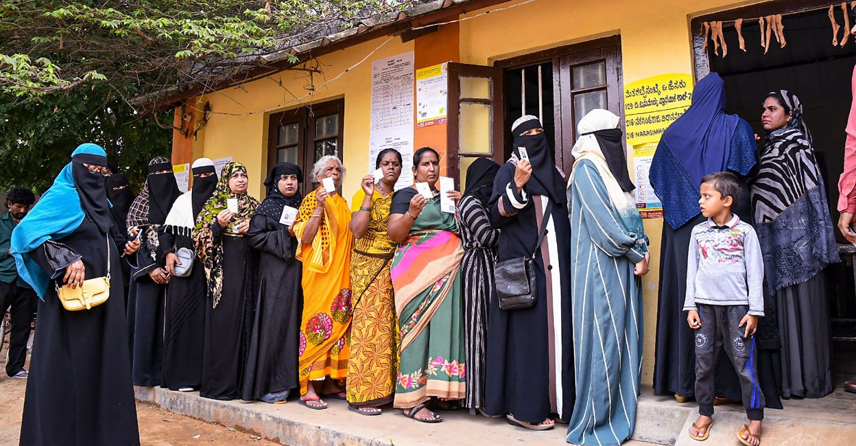 karnataka-polls-2 Voters wait in a queue to cast their votes for Karnataka Assembly elections, at a polling station, in Mysuru district, Wednesday, May 10, 2023. Photo: PTI