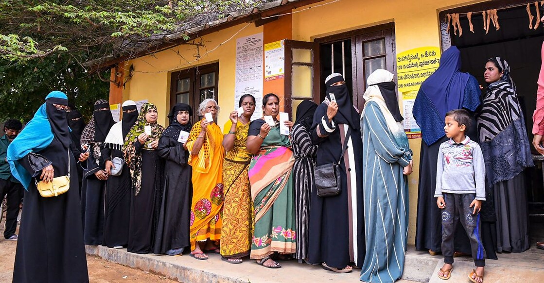 Voters wait in a queue to cast their votes for Karnataka Assembly elections, at a polling station, in Mysuru district, Wednesday, May 10, 2023. Photo: PTI