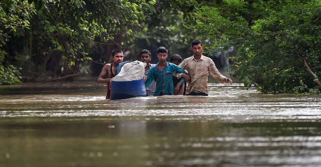People from low-lying areas around the Yamuna river wade through floodwaters of the swollen river while relocating to a safer place, in New Delhi, Wednesday, July 12, 2023. Photo: PTI