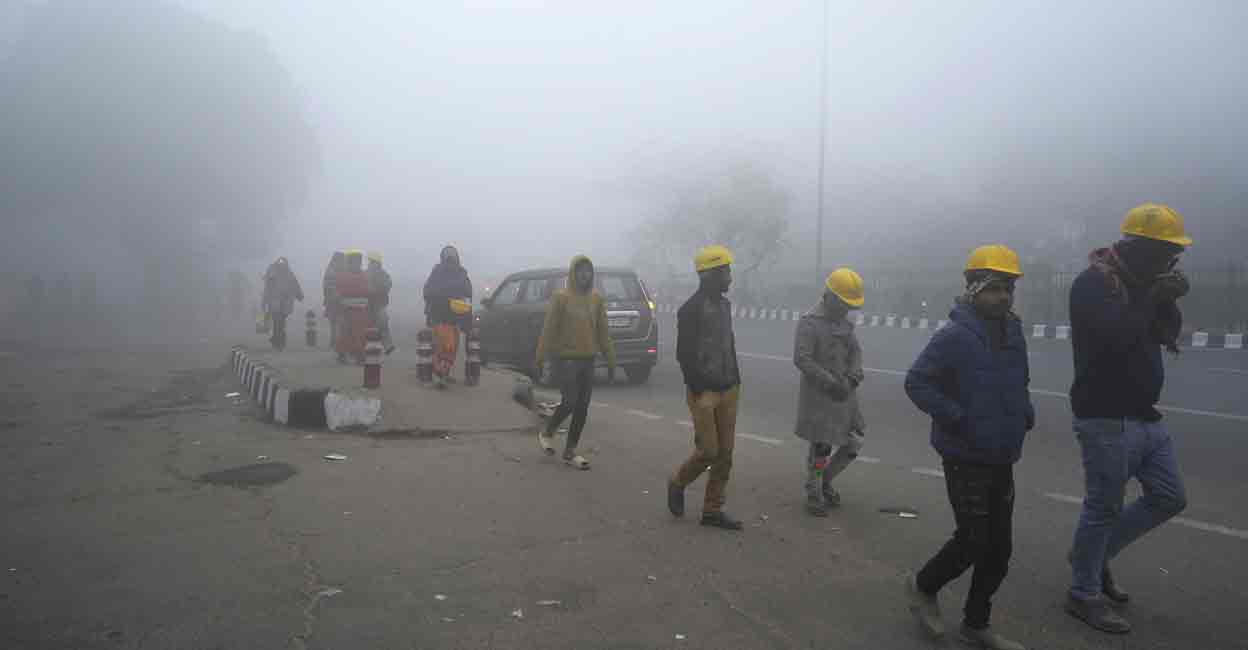 PTI01_14_2024_000021A Labourers walk through fog on a cold winter morning, in New Delhi, Sunday, Jan. 14, 2024. Photo: PTI