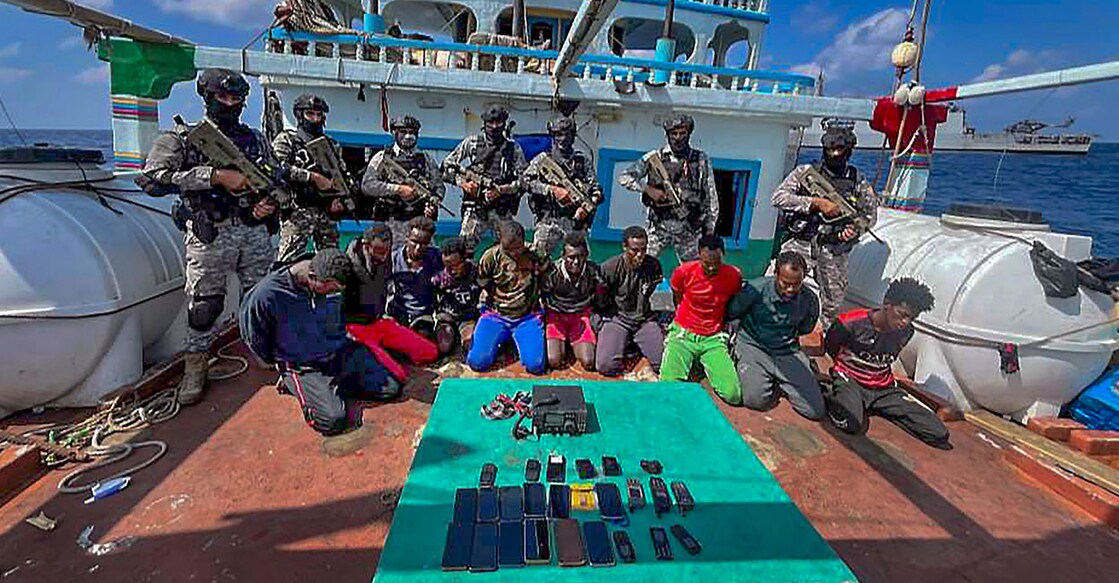 Officials with the captured pirates during an anti-piracy operation by INS Sumitra, rescuing Fishing Vessel Al Naeemi and her Crew (19 Pakistani Nationals) from 11 Somali Pirates off the East Coast of Somalia. Photo: PTI.
