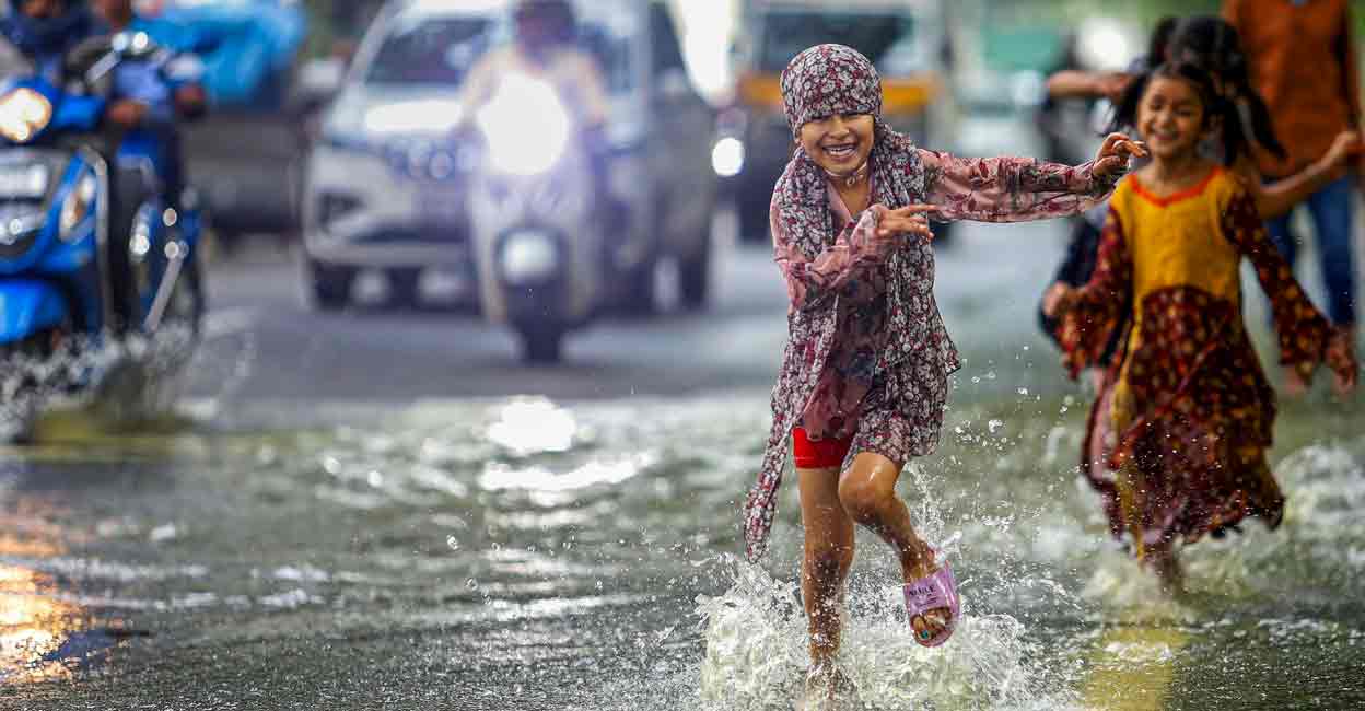 PTI10_21_2024_000104A Children play on a waterlogged road after heavy rain, in Bengaluru, Monday, Oct. 21, 2024. Photo: PTI