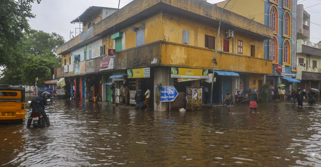 Commuters on a waterlogged road amid rain owing to Cyclone Fengal, in Chennai. Photo: PTI